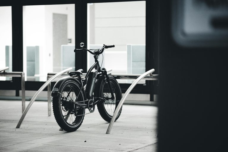 Black and white image of an electric bicycle parked indoors in an urban environment.